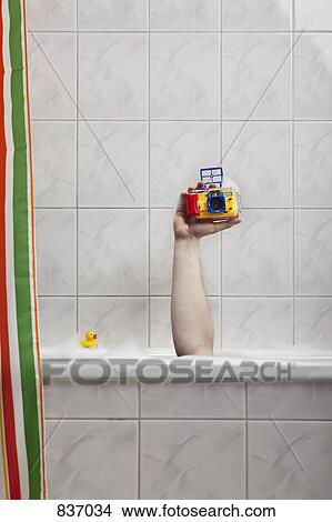 A human hand sticking out of a bathtub holding an underwater camera View Large Photo Image Picture - A human hand sticking out of a bathtub holding an underwater camera. Fotosearch