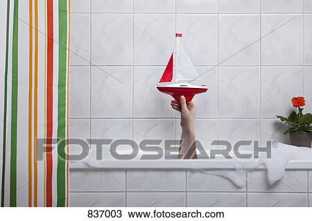A human hand sticking out of a bathtub holding a toy boat View Large Photo Image Stock Image - A human hand sticking out of a bathtub holding a toy boat. Fotosearch
