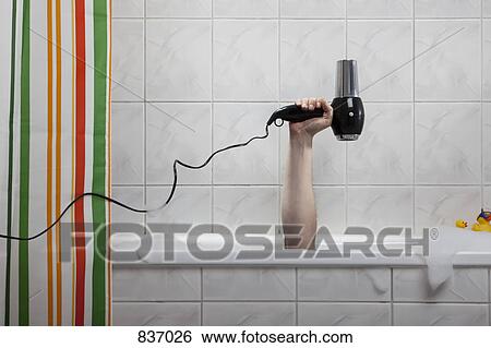 A human hand sticking out of a bathtub holding a hairdryer View Large Photo Image Stock Photograph - A human hand sticking out of a bathtub holding a hairdryer. Fotosearch