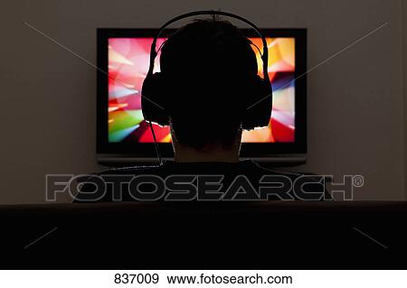 A man wearing headphones and watching television View Large Photo Image Stock Photo - A man wearing headphones and watching television. Fotosearch