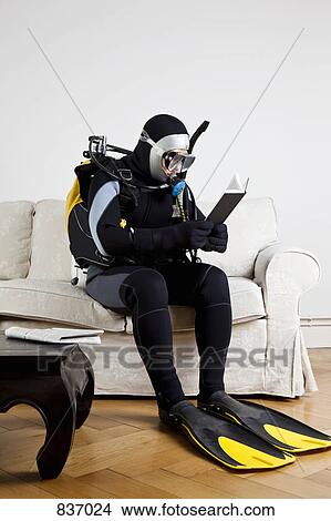 A scuba diver sitting on a couch reading a book View Large Photo Image Picture - A scuba diver sitting on a couch reading a book. Fotosearch