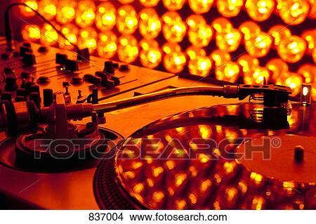 Picture - A turntable and sound mixer illuminated by lighting equipment. Fotosearch