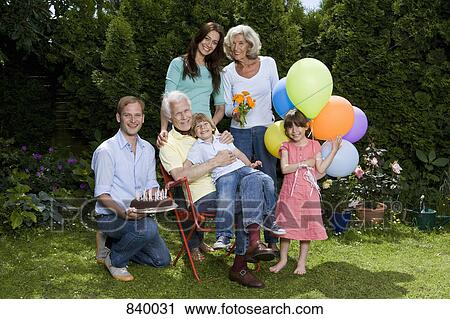 Stock Image - A multi-generational family celebrating a birthday, outdoors. Fotosearch