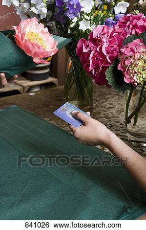 Stock Photograph - A person paying for flowers in a florists. Fotosearch