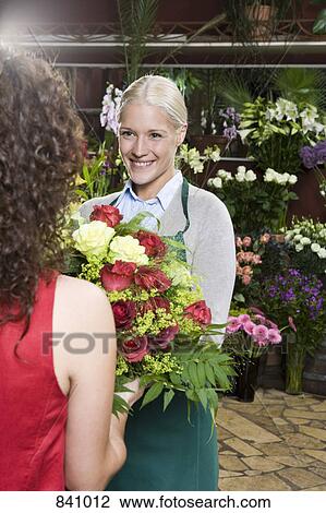 Stock Image - A woman buying a bouquet in a florists. Fotosearch