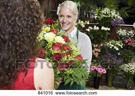 Stock Photograph - A woman buying flowers in a florists. Fotosearch
