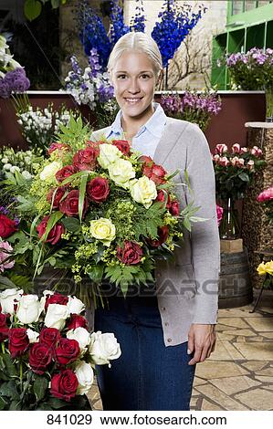 A woman holding a bouquet of roses in a florists View Large Photo Image Stock Photo - A woman holding a bouquet of roses in a florists. Fotosearch