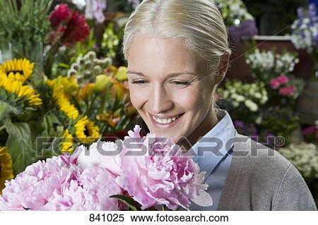 A woman looking at a bunch of flowers and smiling View Large Photo Image Stock Photography - A woman looking at a bunch of flowers and smiling. Fotosearch