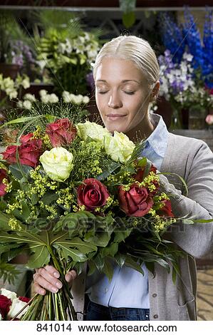 A woman smelling a bouquet of flowers in a florists View Large Photo Image Picture - A woman smelling a bouquet of flowers in a florists. Fotosearch