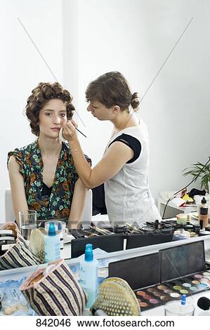 Stock Photograph - A make-up artist applying make-up on a model. Fotosearch