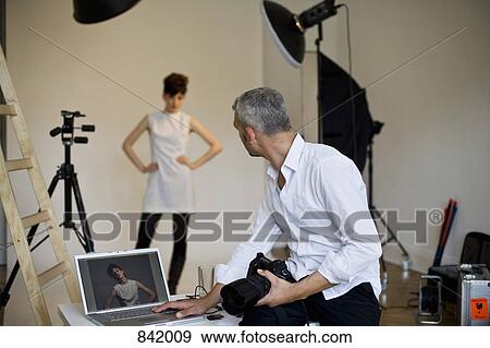 Stock Photo - A photographer using a laptop on set of a fashion shoot. Fotosearch