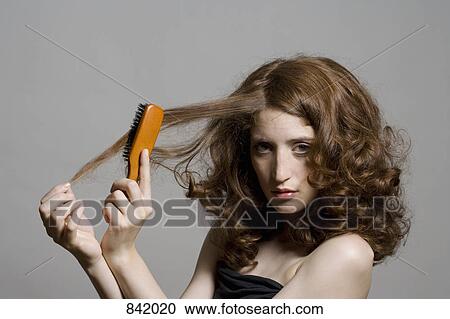 A young woman brushing her hair View Large Photo Image Stock Image - A young woman brushing her hair. Fotosearch