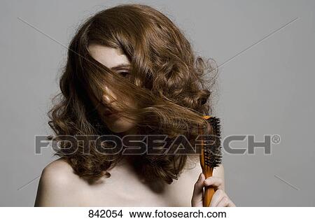 A Young Woman Pulling Hair Over Her Face With A Brush Picture