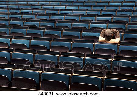A man sitting in an auditorium with his head resting in his arms View Large Photo Image Stock Image - A man sitting in an auditorium with his head resting in his arms. Fotosearch