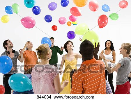 A group of men and women reaching for floating balloons View Large Photo Image Picture - A group of men and women reaching for floating balloons. Fotosearch