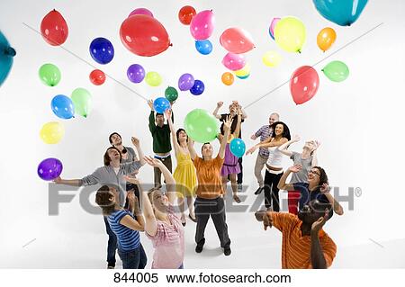 A group of men and women reaching for floating balloons View Large Photo Image Stock Photography - A group of men and women reaching for floating balloons. Fotosearch