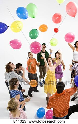 A group of young adults reaching for floating balloons View Large Photo Image Stock Image - A group of young adults reaching for floating balloons. Fotosearch
