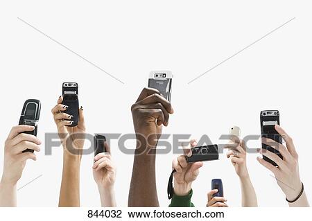 Stock Image - Detail of people with raised hands and holding mobile phones. Fotosearch