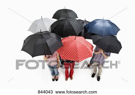 Stock Image - Group of men and women standing under umbrellas. Fotosearch