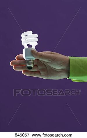 A hand holding out an energy saving light bulb View Large Photo Image Stock Photo - A hand holding out an energy saving light bulb. Fotosearch