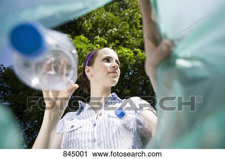 Stock Image - A woman throwing a plastic bottle away. Fotosearch