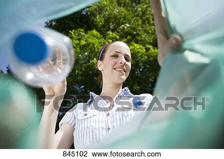 Stock Image - A woman throwing a plastic bottle away. Fotosearch