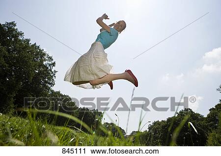 A young woman jumping in a field View Large Photo Image Stock Image - A young woman jumping in a field. Fotosearch