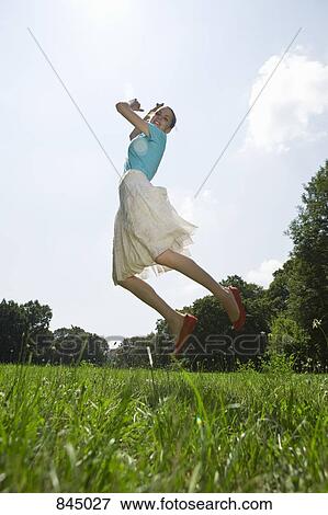A young woman jumping in a field View Large Photo Image Stock Photo - A young woman jumping in a field. Fotosearch