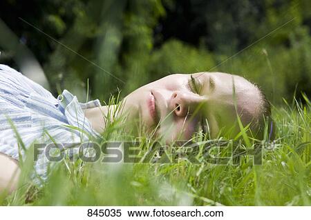 A young woman lying in grass sleeping View Large Photo Image Stock Photography - A young woman lying in grass sleeping. Fotosearch