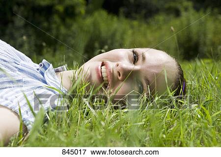 Stock Photo - A young woman lying in grass. Fotosearch