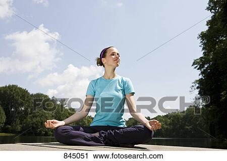 A young woman practicing yoga on a jetty View Large Photo Image Stock Image - A young woman practicing yoga on a jetty. Fotosearch