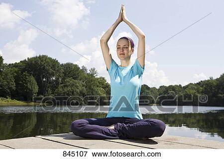 A young woman practicing yoga on a jetty View Large Photo Image Stock Photo - A young woman practicing yoga on a jetty. Fotosearch