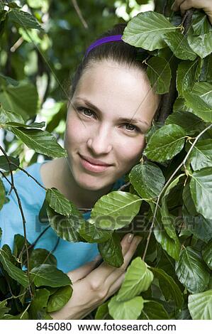Portrait of a young woman's face framed by leaves View Large Photo Image Stock Image - Portrait of a young woman's face framed by leaves. Fotosearch