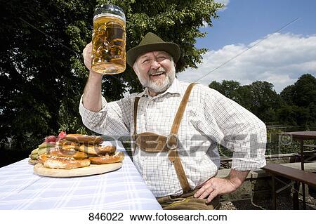 A traditionally clothed German man in a beer garden raising his beer glass in toast View Large Photo Image Stock Image - A traditionally clothed German man in a beer garden raising his beer glass in toast. Fotosearch
