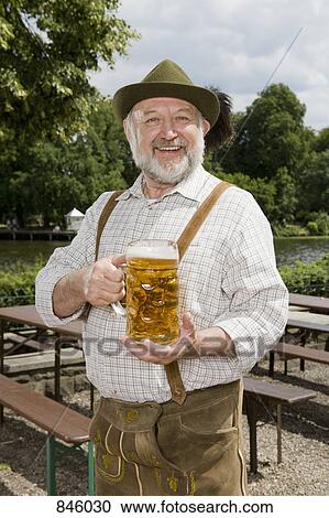 A traditionally clothed German man in a beer garden holding a beer glass View Large Photo Image Stock Image - A traditionally clothed German man in a beer garden holding a beer glass . Fotosearch