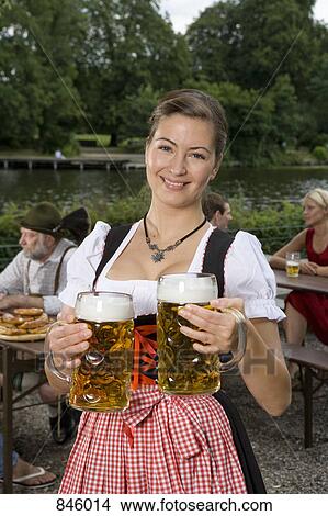 A traditionally clothed German woman serving beer in a beer garden View Large Photo Image Picture - A traditionally clothed German woman serving beer in a beer garden. Fotosearch