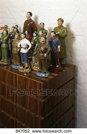 Stock Image - Communist ceramic figurines arranged on a wooden cabinet. Fotosearch
