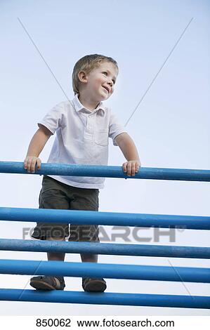 A boy standing at the top of a jungle gym View Large Photo Image Stock Image - A boy standing at the top of a jungle gym. Fotosearch