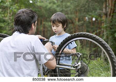 A father and son fixing a bicycle together View Large Photo Image Stock Photo - A father and son fixing a bicycle together. Fotosearch