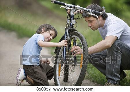 Stock Photo - A father and son repairing a bicycle. Fotosearch
