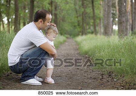Stock Photography - A father crouching with his baby daughter on a rural path. Fotosearch