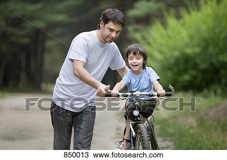 A father teaching his son to ride a bicycle View Large Photo Image Stock Image - A father teaching his son to ride a bicycle. Fotosearch