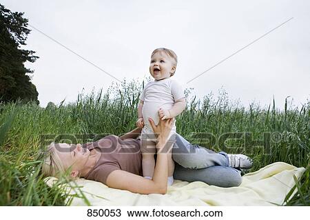 A mother and baby daughter playing on a rug in a field View Large Photo Image Stock Image - A mother and baby daughter playing on a rug in a field. Fotosearch