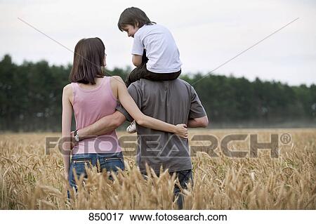 A young family walking through a wheat field View Large Photo Image Stock Photo - A young family walking through a wheat field. Fotosearch
