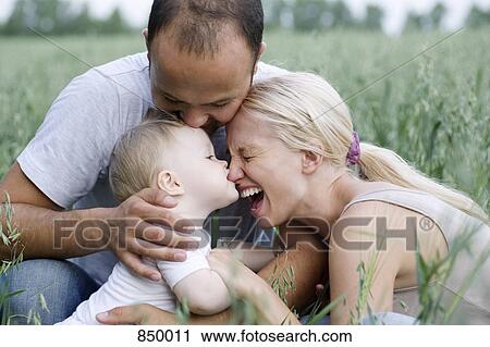 Two parents and their baby daughter in a field View Large Photo Image Stock Image - Two parents and their baby daughter in a field. Fotosearch