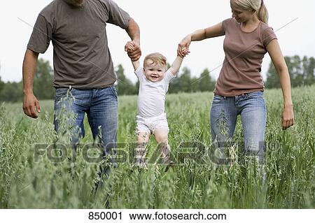 Two parents lifting a child in the air View Large Photo Image Stock Image - Two parents lifting a child in the air. Fotosearch
