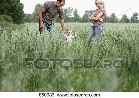 Two parents playing with their daughter in a field View Large Photo Image Stock Image - Two parents playing with their daughter in a field. Fotosearch
