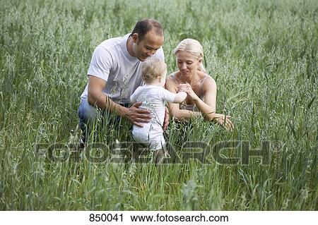Two parents playing with their daughter in a field View Large Photo Image Stock Image - Two parents playing with their daughter in a field. Fotosearch