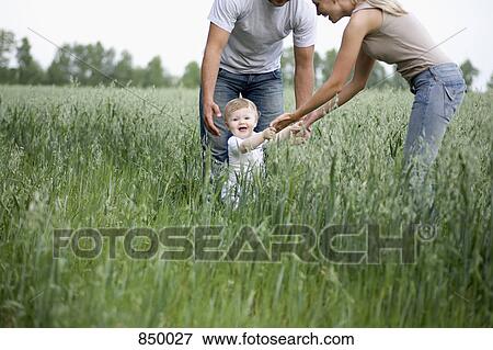 Two parents playing with their daughter in a field View Large Photo Image Stock Photo - Two parents playing with their daughter in a field. Fotosearch