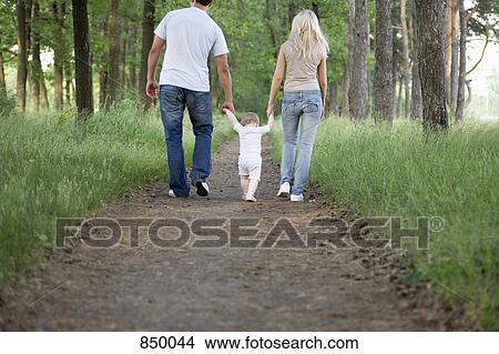 Two parents walking along a forest path with their young daughter View Large Photo Image Picture - Two parents walking along a forest path with their young daughter. Fotosearch